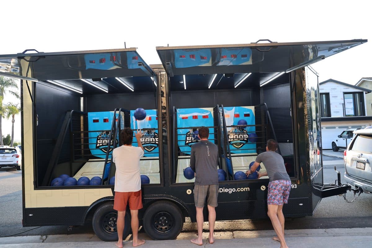 Family playing arcade basketball at the open Hoop San Diego trailer