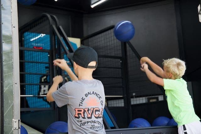 Two kids shooting hoops inside the arcade trailer